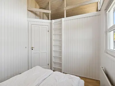 a bedroom with white walls and a bed and a window at Holiday Home Alrune - 800m from the sea by Interhome in Blokhus