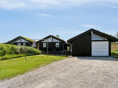 a house with a garage and a gravel driveway at Holiday Home Alrune - 800m from the sea by Interhome in Blokhus