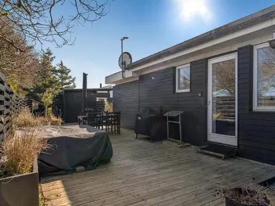 a wooden deck next to a house at Holiday Home Ozan - 400m from the sea by Interhome in Blokhus
