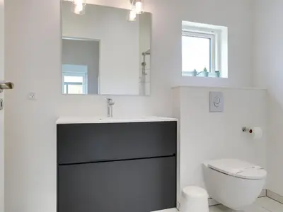 a bathroom with a sink and a toilet and a mirror at Holiday Home Antonina - 800m from the sea by Interhome in Blokhus