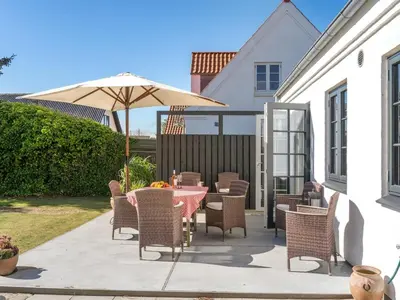 a patio with a table and chairs and an umbrella at Holiday Home Shiva - 300m from the sea by Interhome in Blokhus