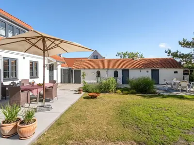 a patio with a table and an umbrella in a yard at Holiday Home Shiva - 300m from the sea by Interhome in Blokhus