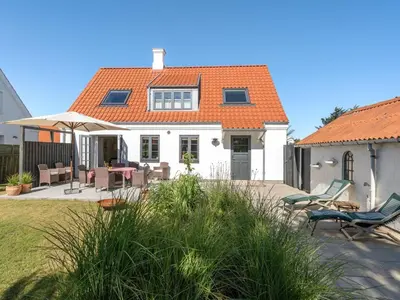 a white house with an orange roof and a patio at Holiday Home Shiva - 300m from the sea by Interhome in Blokhus