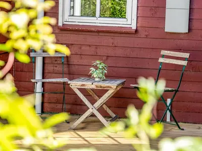 a table and two chairs next to a red wall at Holiday Home Ansberga - 1km from the sea by Interhome in Blokhus