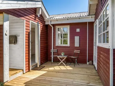 a small patio with a table on a wooden deck at Holiday Home Ansberga - 1km from the sea by Interhome in Blokhus