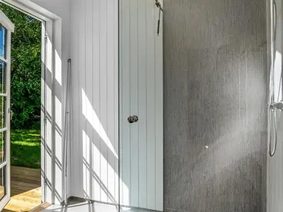 a bathroom with a walk in shower next to a door at Holiday Home Ansberga - 1km from the sea by Interhome in Blokhus
