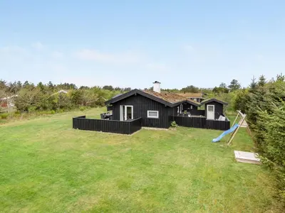 a black house with a slide in a yard at Holiday Home Birette - 1-5km from the sea by Interhome in Blokhus