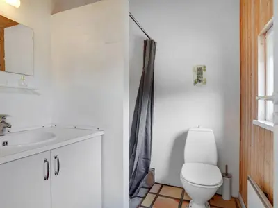 a white bathroom with a toilet and a sink at Holiday Home Birette - 1-5km from the sea by Interhome in Blokhus