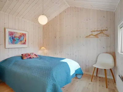 a bedroom with a blue bed and a white chair at Holiday Home Birette - 1-5km from the sea by Interhome in Blokhus