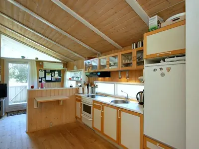 a kitchen with wooden cabinets and a white refrigerator at Holiday Home Anthonia - 1-6km from the sea by Interhome in Blokhus