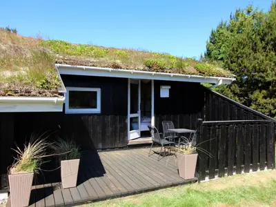 a black house with a grass roof with a deck at Holiday Home Anthonia - 1-6km from the sea by Interhome in Blokhus