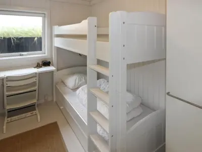a room with bunk beds and a desk and a window at Holiday Home Fenneke - 50m from the sea by Interhome in Blokhus