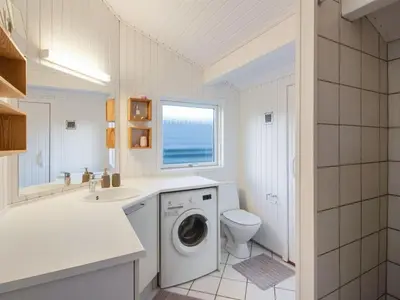 a bathroom with a washing machine and a sink at Holiday Home Fenneke - 50m from the sea by Interhome in Blokhus