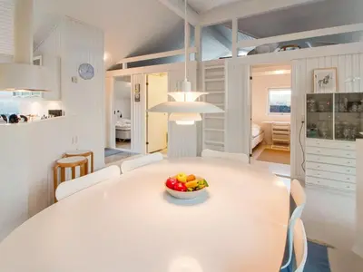 a white kitchen with a table with a bowl of fruit on it at Holiday Home Fenneke - 50m from the sea by Interhome in Blokhus