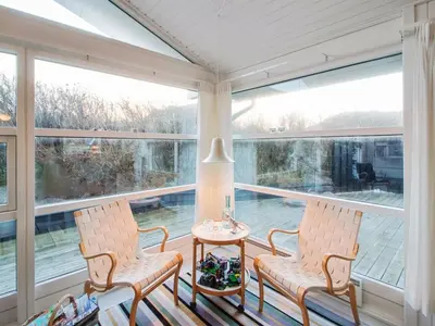 two chairs and a table in a room with large windows at Holiday Home Fenneke - 50m from the sea by Interhome in Blokhus