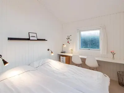 a bedroom with a bed and a desk and a window at Holiday Home Fenneke - 50m from the sea by Interhome in Blokhus