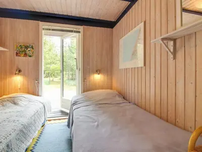 two beds in a room with wooden walls and a window at Holiday Home Heike - 1-3km from the sea by Interhome in Blokhus
