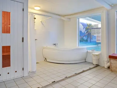 a white bathroom with a tub and a window at Holiday Home Pelle - 800m from the sea by Interhome in Blokhus