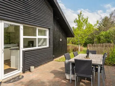 a patio with a table and chairs and a building at Holiday Home Pelle - 800m from the sea by Interhome in Blokhus
