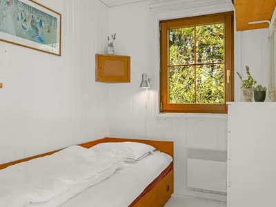 a white bedroom with a bed and a window at Holiday Home Eimi - 1-5km from the sea by Interhome in Blokhus