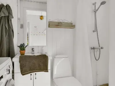 a white bathroom with a toilet and a sink at Holiday Home Eimi - 1-5km from the sea by Interhome in Blokhus
