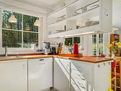 a white kitchen with white cabinets and windows at Holiday Home Eimi - 1-5km from the sea by Interhome in Blokhus