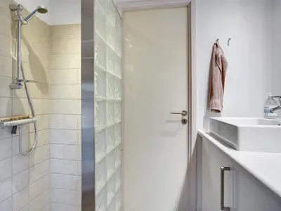 a white bathroom with a shower and a sink at Holiday Home Anahi - 3km from the sea by Interhome in Blokhus