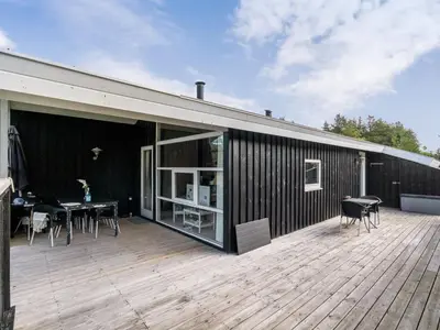 a patio with a table and chairs on a wooden deck at Holiday Home Anahi - 3km from the sea by Interhome in Blokhus