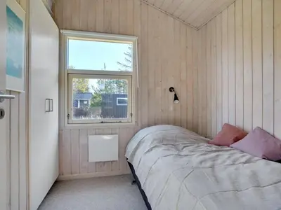 a small bedroom with a bed and a window at Holiday Home Anahi - 3km from the sea by Interhome in Blokhus