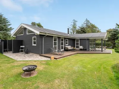 a black house with a grill in the yard at Holiday Home Onta - 900m from the sea by Interhome in Blokhus