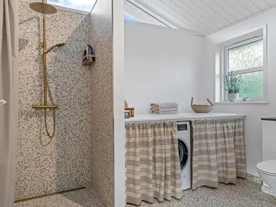 a bathroom with a shower and a washer and dryer at Holiday Home Onta - 900m from the sea by Interhome in Blokhus