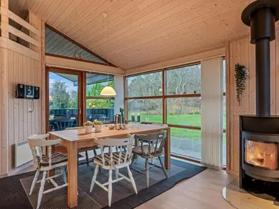 a dining room with a wooden table and a fireplace at Holiday Home Jelin - 2-5km from the sea by Interhome in Blokhus