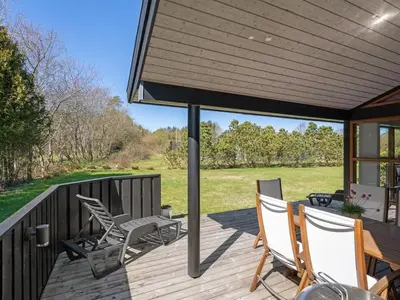 a covered deck with chairs and a table at Holiday Home Jelin - 2-5km from the sea by Interhome in Blokhus