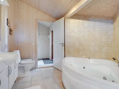 a bathroom with a white tub and a toilet at Holiday Home Jelin - 2-5km from the sea by Interhome in Blokhus