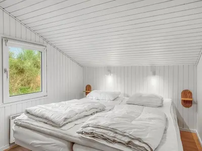 a white bed in a room with a window at Holiday Home Helene - 1-5km from the sea by Interhome in Blokhus