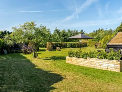 a garden with a brick wall and an umbrella at Holiday Home Ingimar - 2-2km from the sea by Interhome in Blokhus