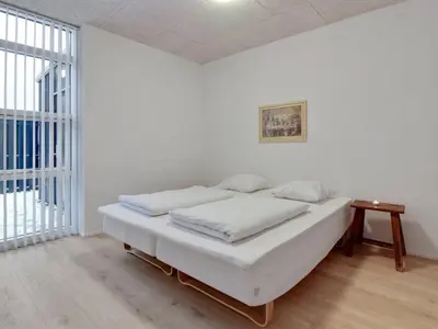 a white room with a bed and a table at Holiday Home Klaudius - 2km from the sea by Interhome in Blokhus