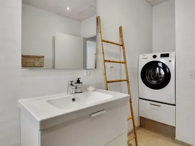 a bathroom with a sink and a washing machine at Holiday Home Klaudius - 2km from the sea by Interhome in Blokhus