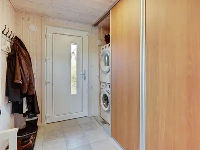 a laundry room with a washing machine and a door at Holiday Home Henric - 100m from the sea by Interhome in Blokhus