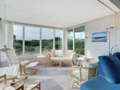 a living room with white furniture and large windows at Holiday Home Henric - 100m from the sea by Interhome in Blokhus