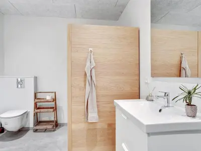 a bathroom with a white sink and a wooden door at Holiday Home Ilsabe - 2km from the sea by Interhome in Blokhus