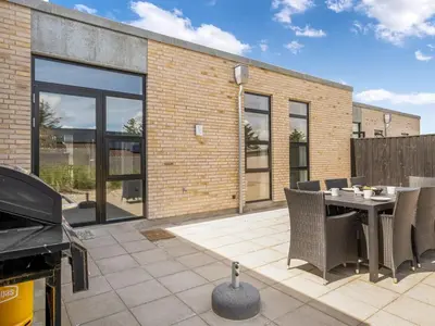 a patio with a table and chairs and a grill at Holiday Home Ilsabe - 2km from the sea by Interhome in Blokhus