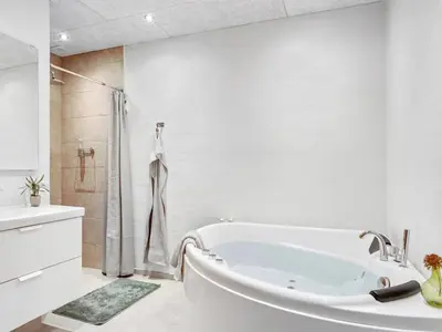 a white bathroom with a tub and a shower at Holiday Home Ilsabe - 2km from the sea by Interhome in Blokhus
