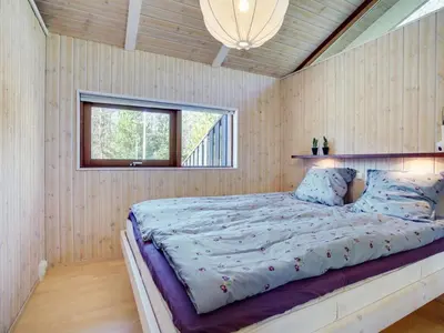 a large bed in a room with a window at Holiday Home Angja - 800m from the sea by Interhome in Blokhus