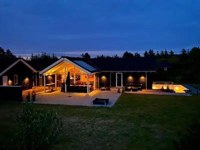 a house with a large deck in the yard at night at Holiday Home Ancel - 1-7km from the sea by Interhome in Blokhus