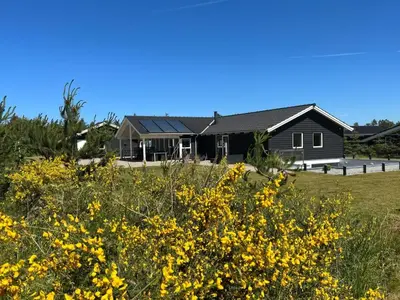 a house with a field of yellow flowers at Holiday Home Ancel - 1-7km from the sea by Interhome in Blokhus
