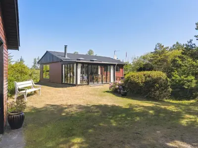 a small house with a bench in a yard at Holiday Home Lykka - 950m from the sea by Interhome in Blokhus