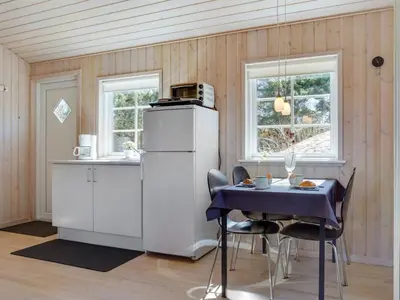 a kitchen with a table and a refrigerator at Holiday Home Amie - 800m from the sea by Interhome in Blokhus