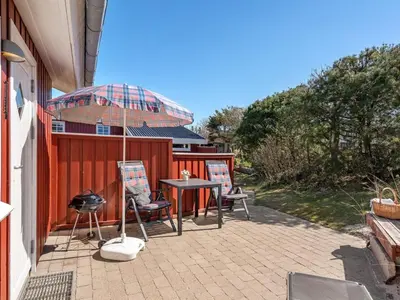 a patio with two chairs and a table and an umbrella at Holiday Home Amie - 800m from the sea by Interhome in Blokhus