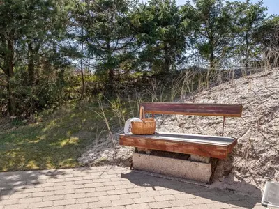 a wooden bench sitting on the side of a hill at Holiday Home Amie - 800m from the sea by Interhome in Blokhus